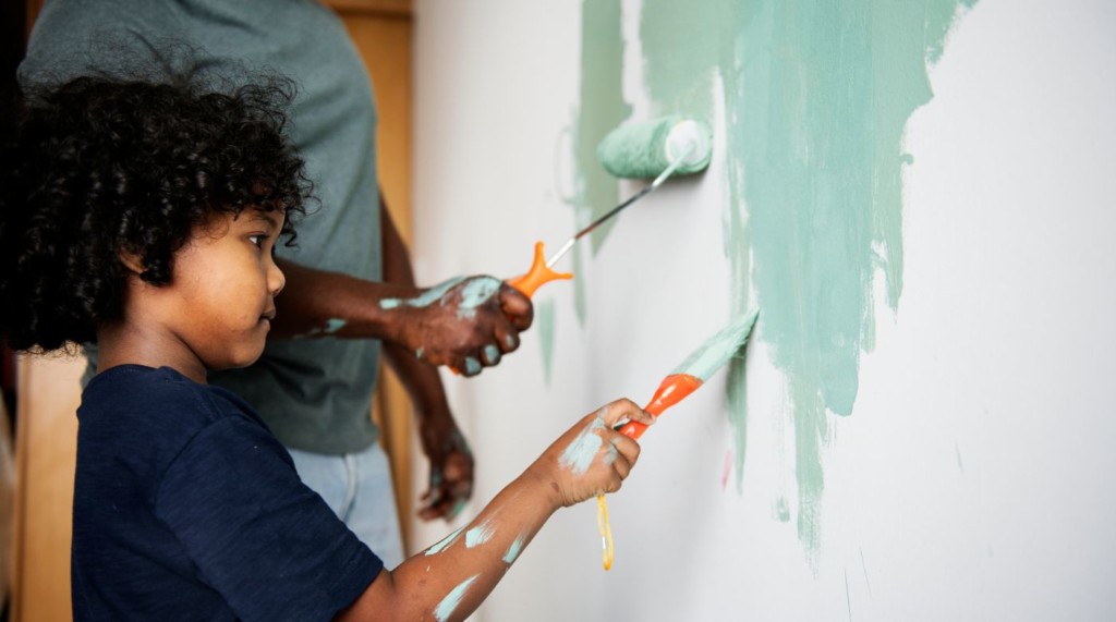 Little girl painting a wall.