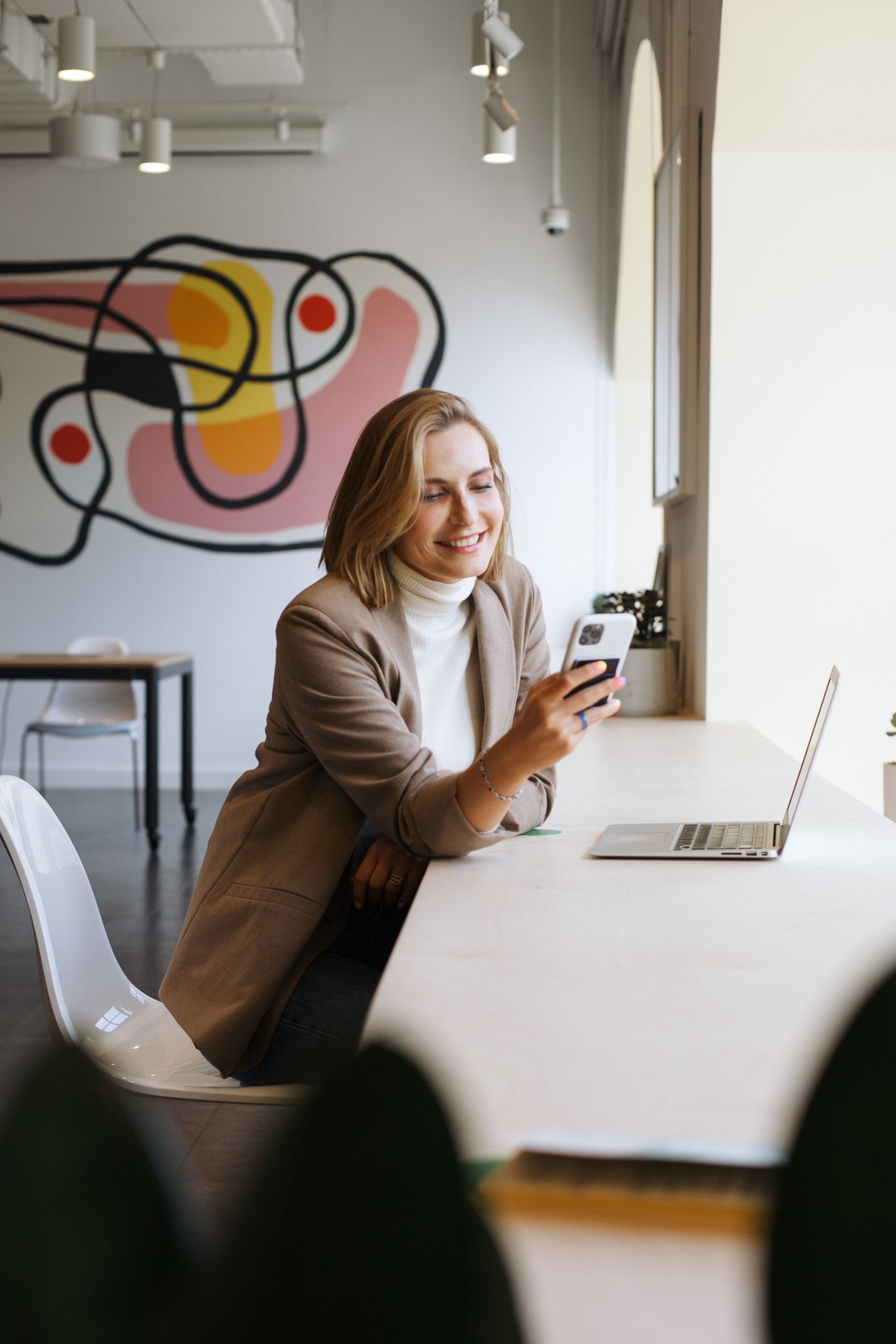 Woman looking at her cell phone and smiling - An exceptional career - The best tools in the industry - Careers | Multi-Prêts Hypothèques